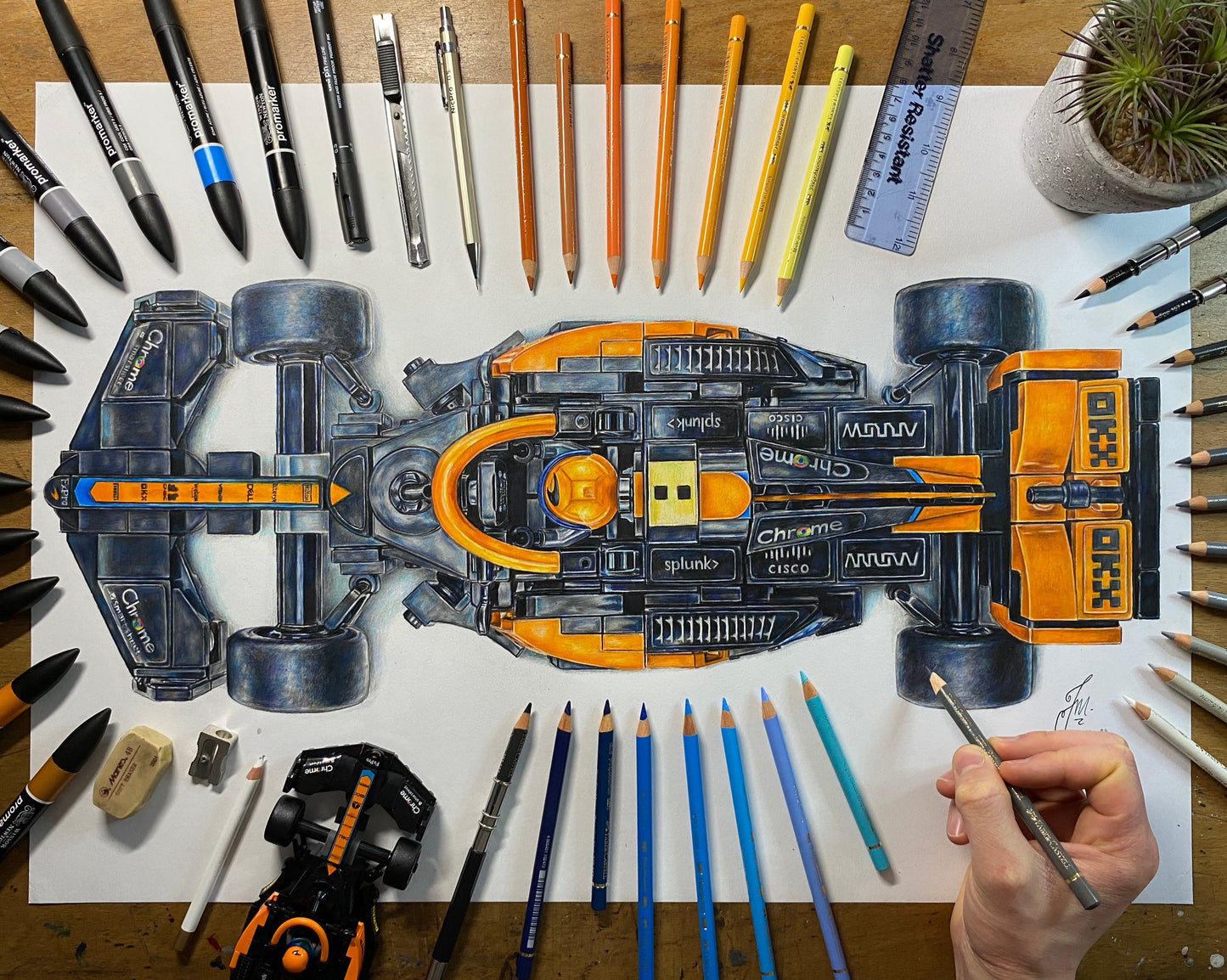 My realistoc coloured pencil drawing of the LEGO Mclaren F1 car surrounded by art materials